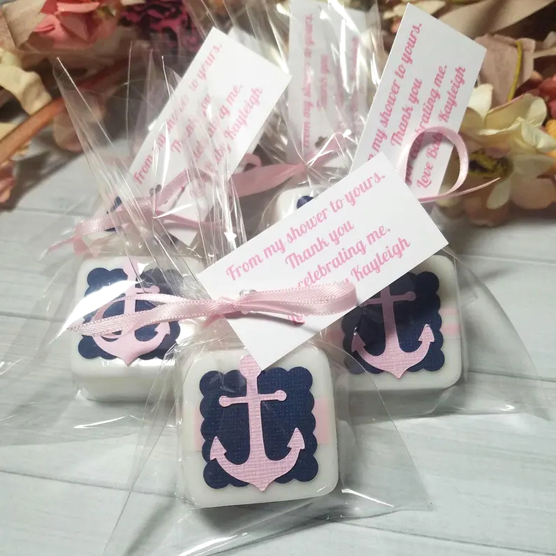 Decorative soap bars with anchor design and pink ribbons in clear packaging.