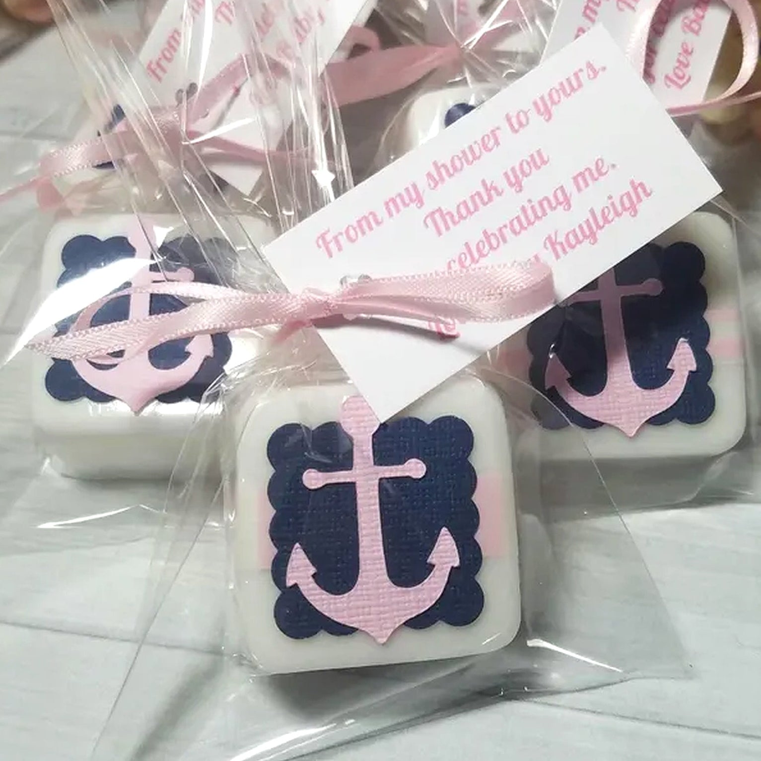 Decorative soap bars with anchor design and pink ribbons in clear packaging.